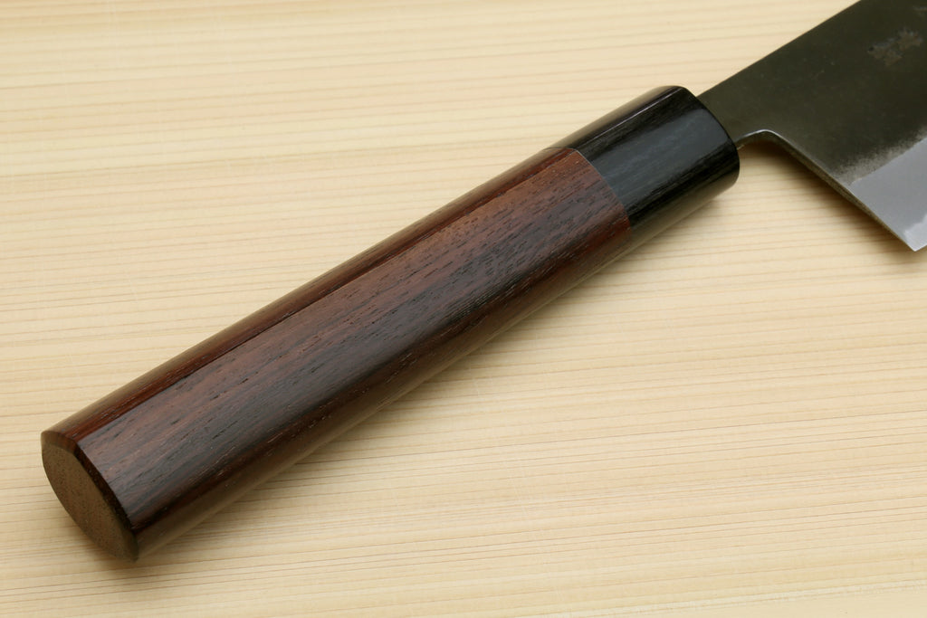 Nakiri cleaver with dark wooden handle and straight black-finished blade on a board
