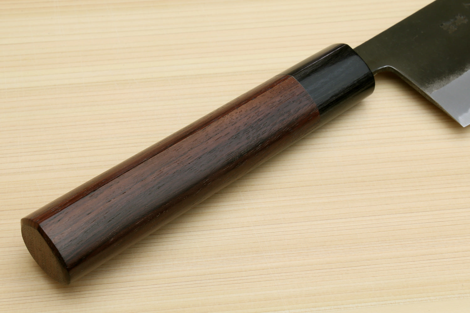 Nakiri cleaver with dark wooden handle and straight black-finished blade on a board