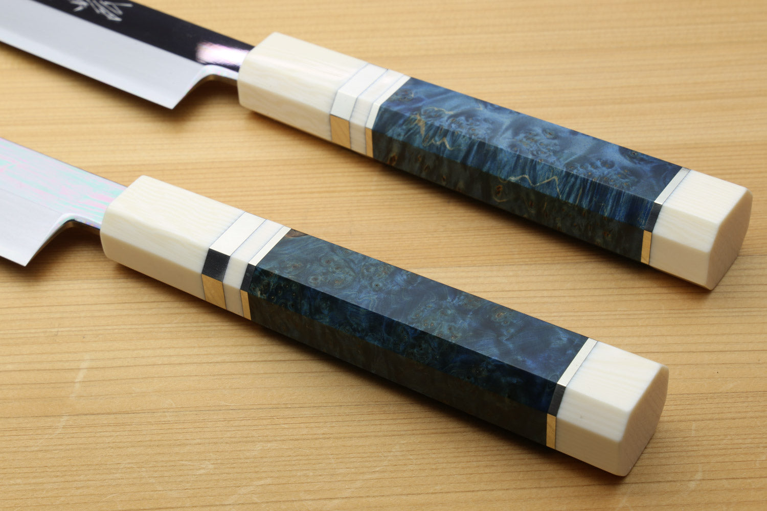 Yanagi knife handles side-by-side: pale ivory grips with blue patterned bands