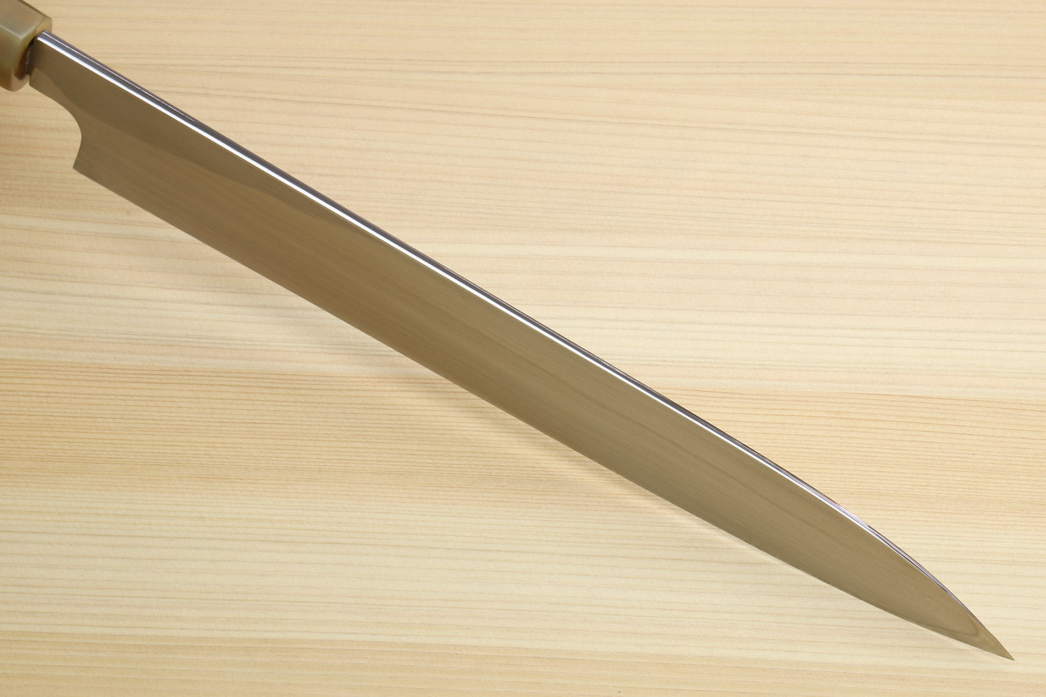 Yanagiba sushi knife blade profile on light wood surface, no handle focus