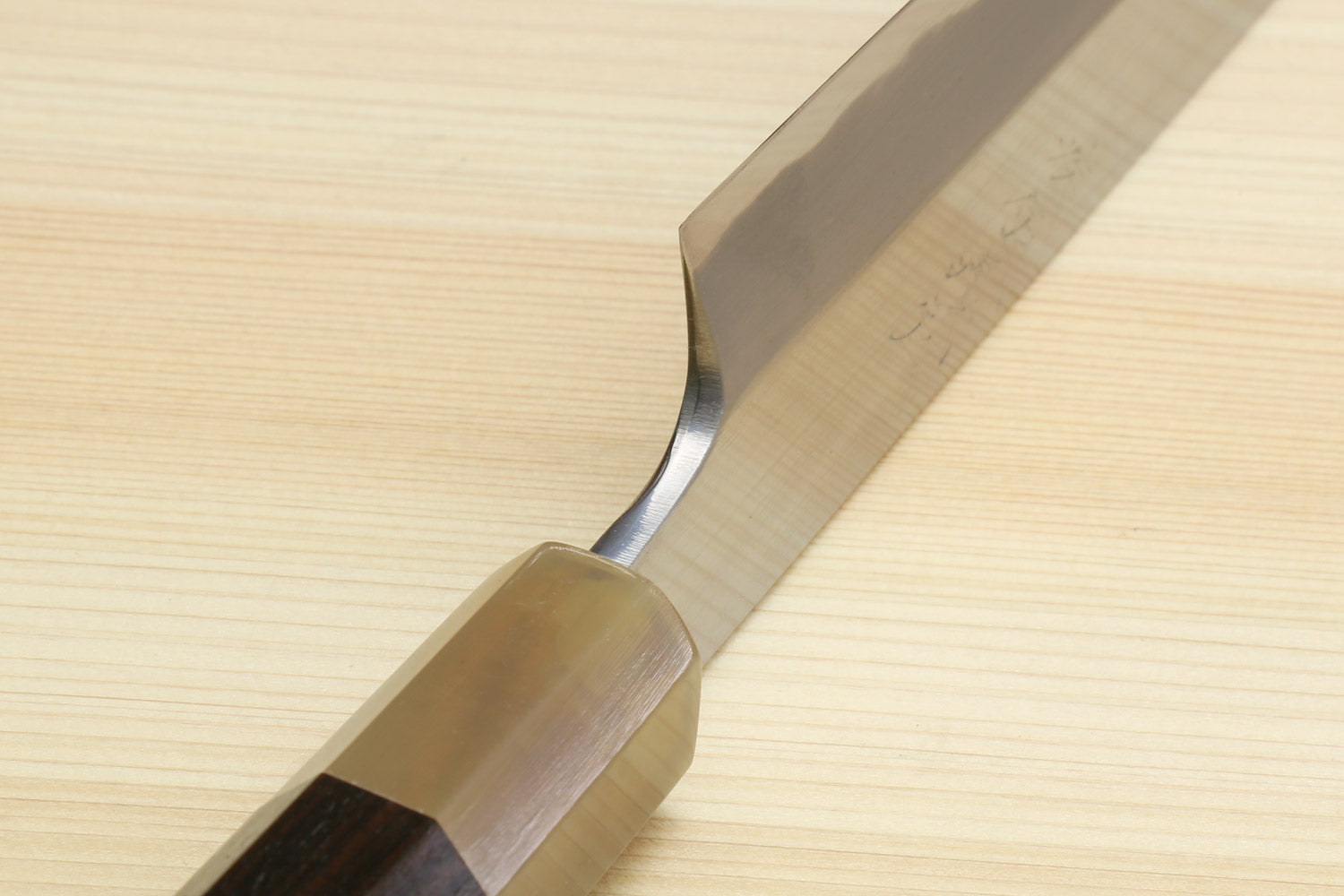 Yanagiba sushi knife bolster and handle joint with white blade edge close-up