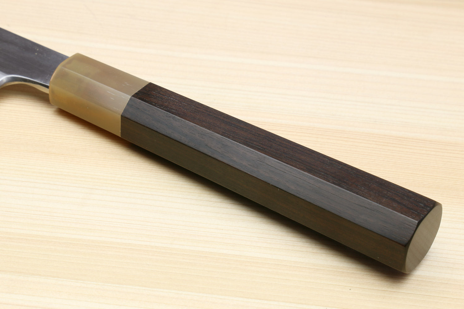 Ebony-handled yanagiba sushi knife with dark metallic blade near the spine