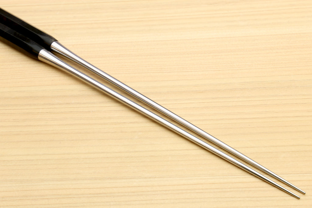 Metal-tipped plating tweezers with ebony bases, shown in close-up on wood