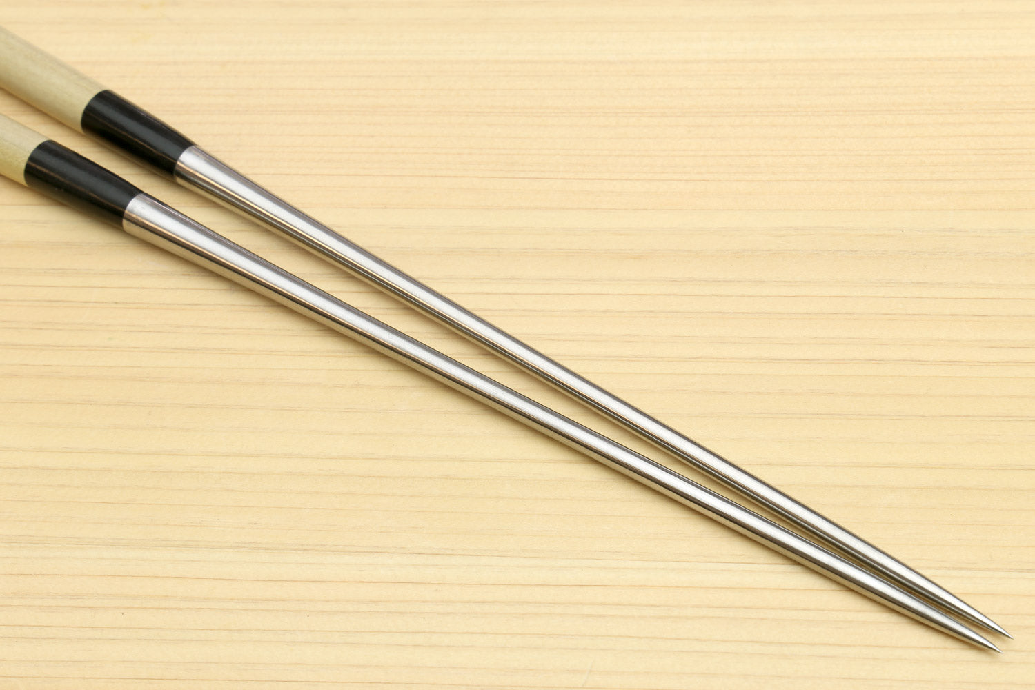 Two sushi tweezers with light wood handles and stainless steel pointed ends