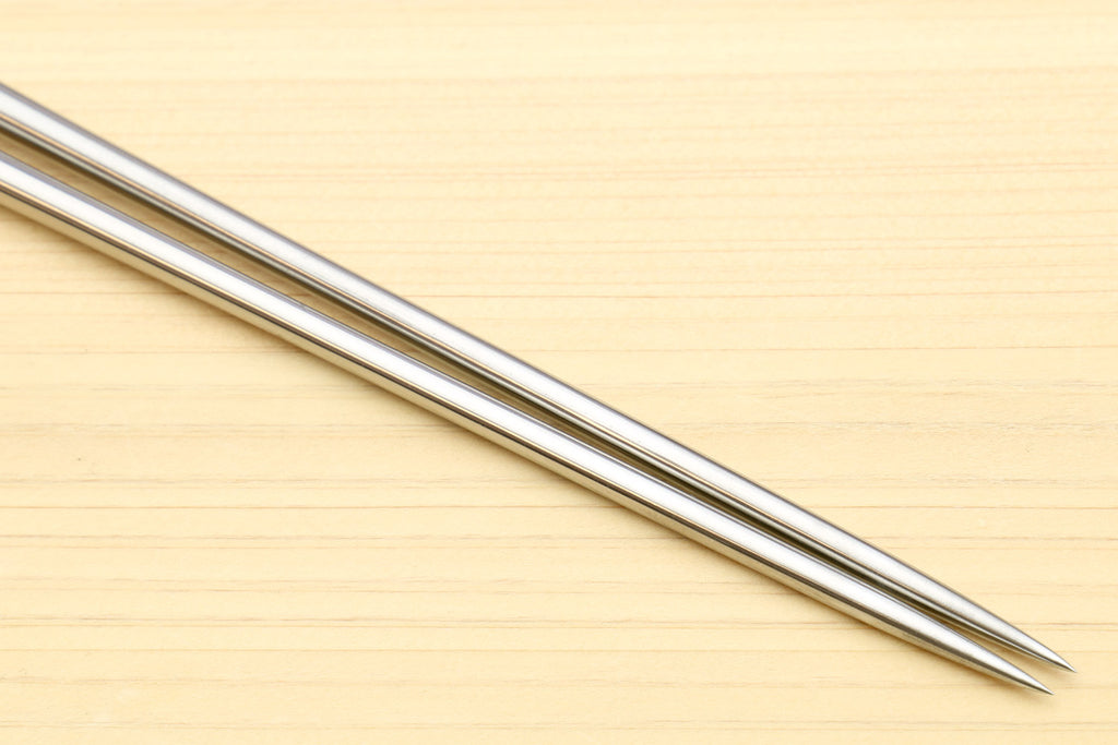 Close-up of stainless steel pointed tips on light wood sushi tweezers
