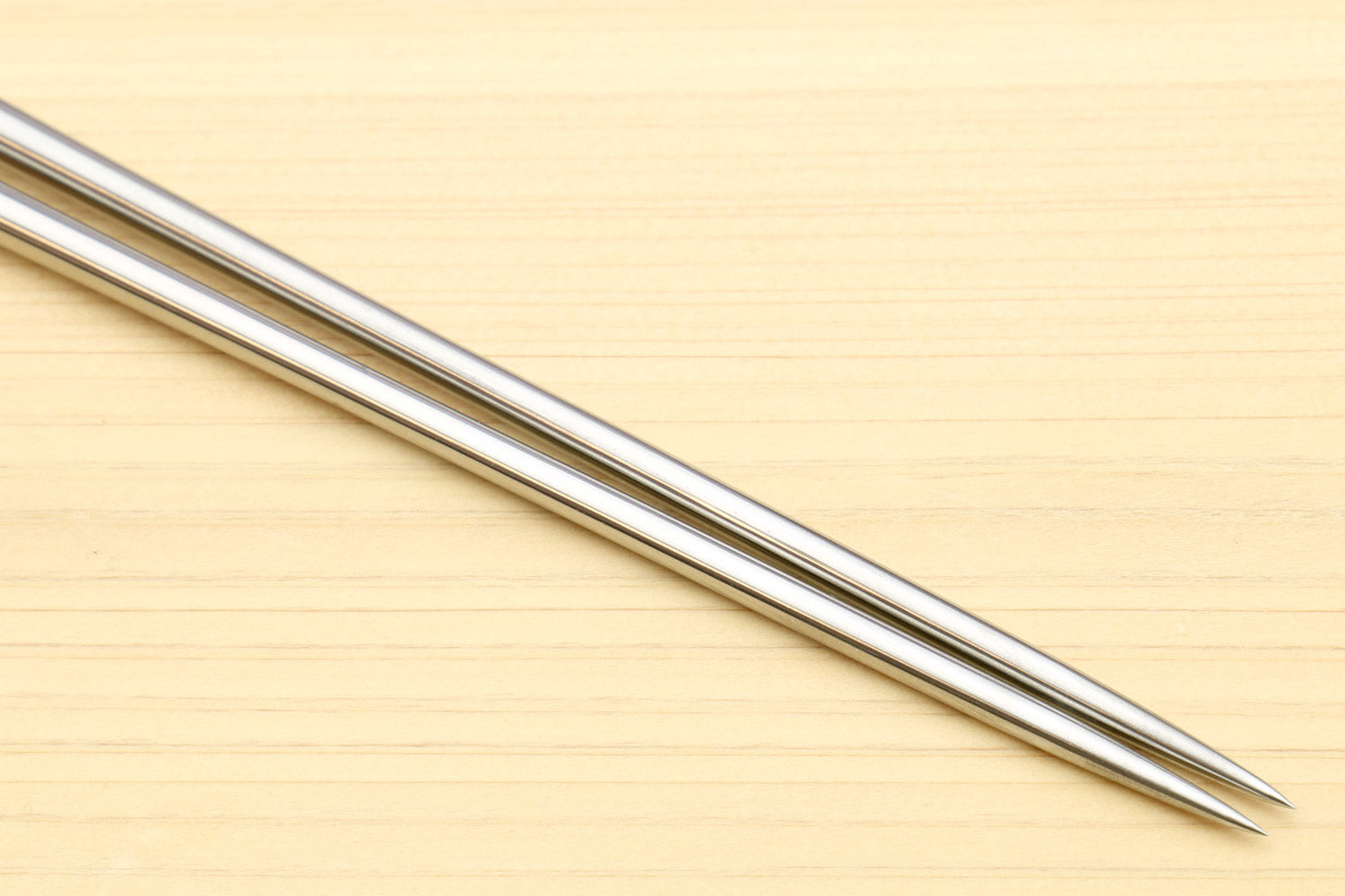 Close-up of stainless steel pointed tips on light wood sushi tweezers