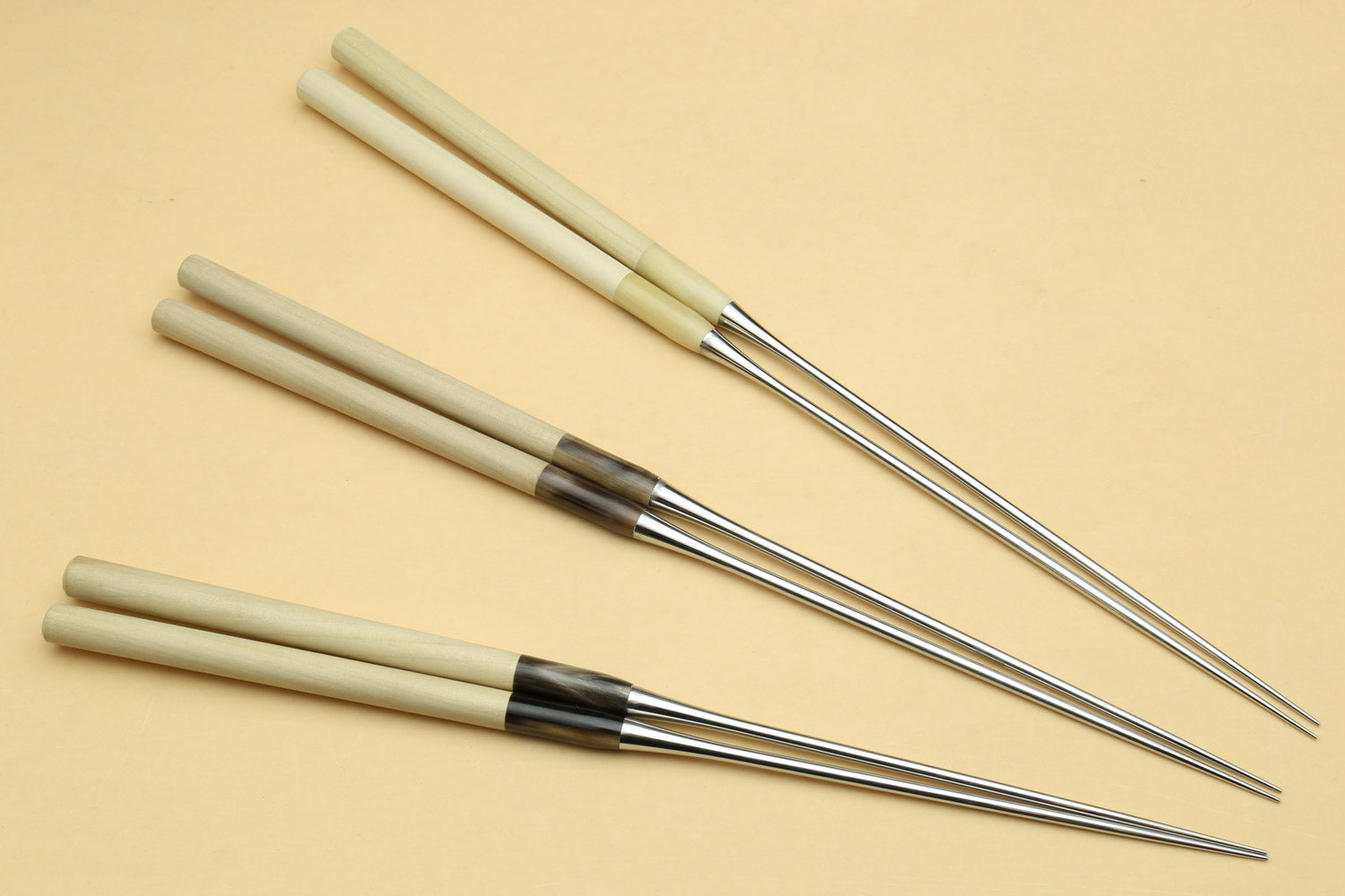 Four sushi plating tweezers with light wooden handles and stainless pointed tips