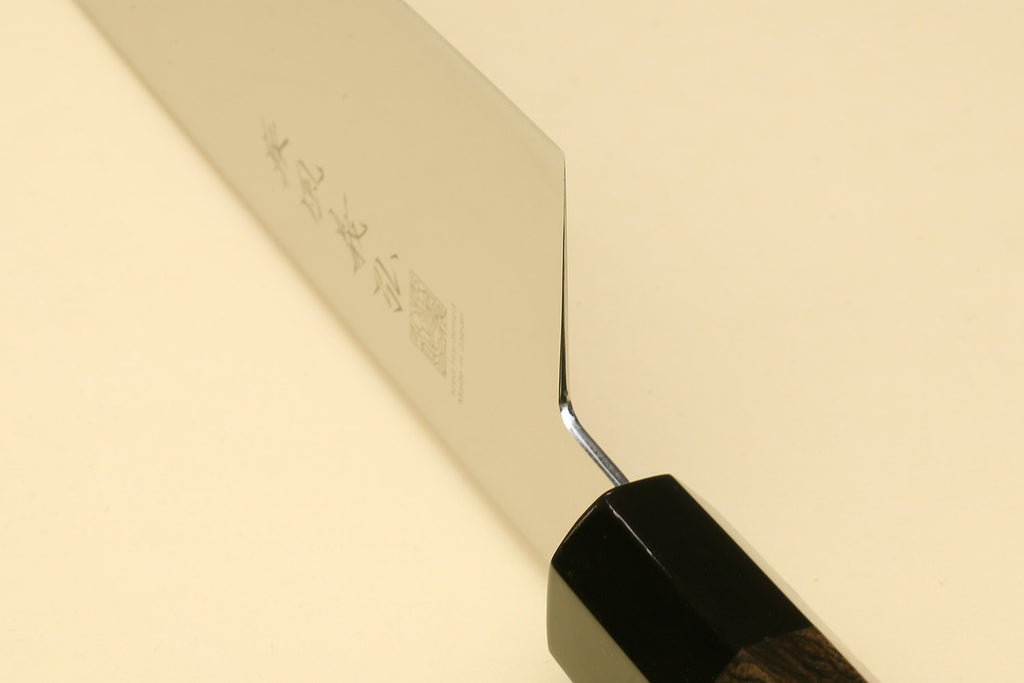 Stainless knife blade tip close-up with engraved marking and black handle scales
