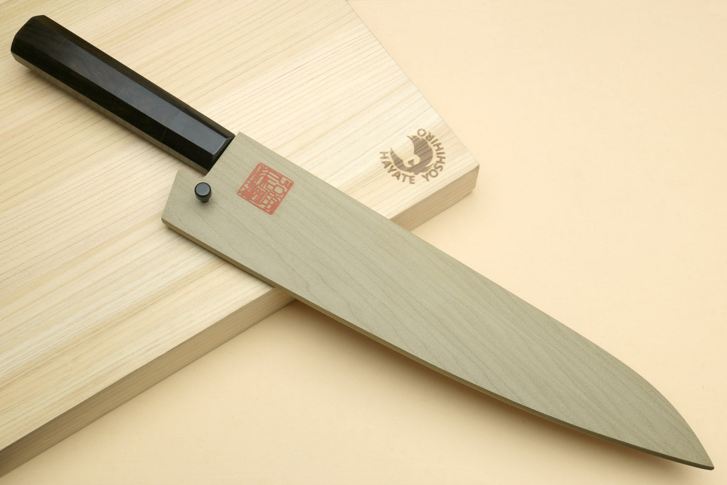 Gyuto chef knife on wooden board with dark handle and stainless blade profile