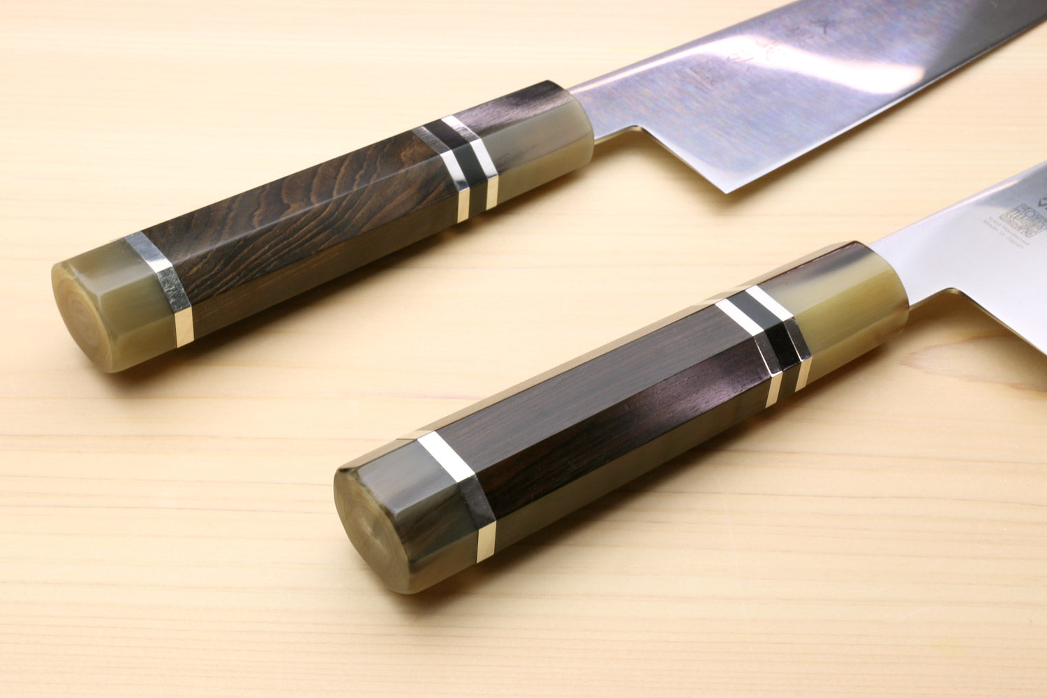 Japanese chef knife showing dark octagonal handles with ring accents