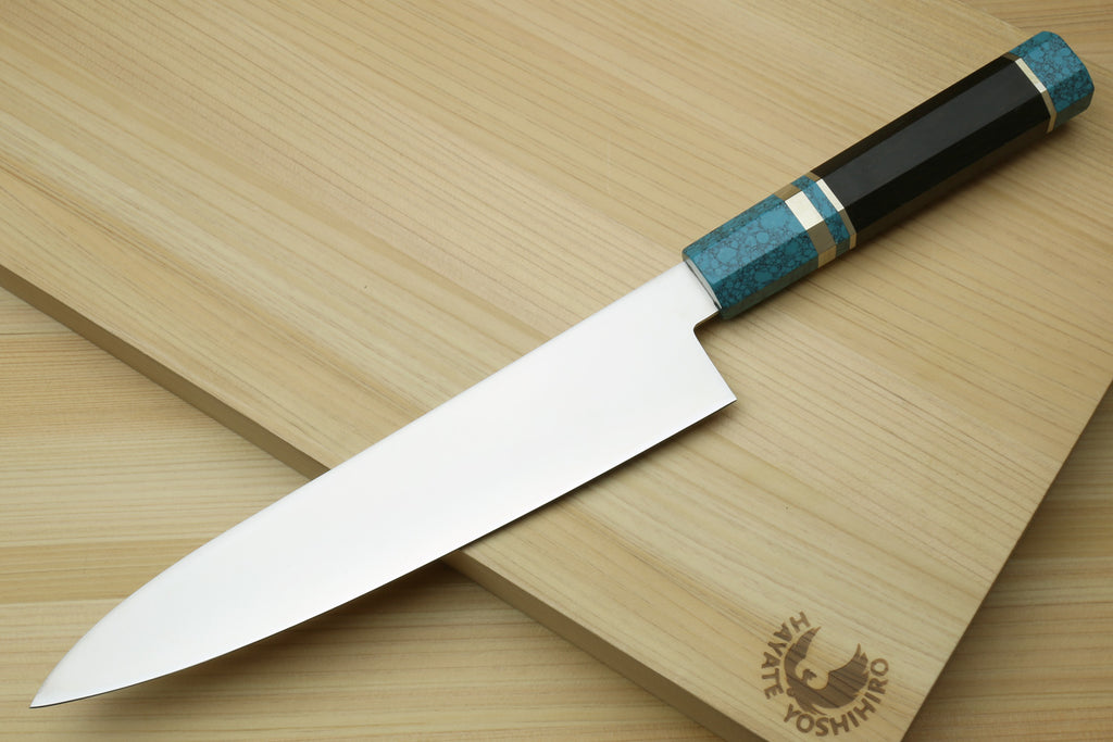 Stainless steel gyuto chef knife with turquoise blue handle on wooden board