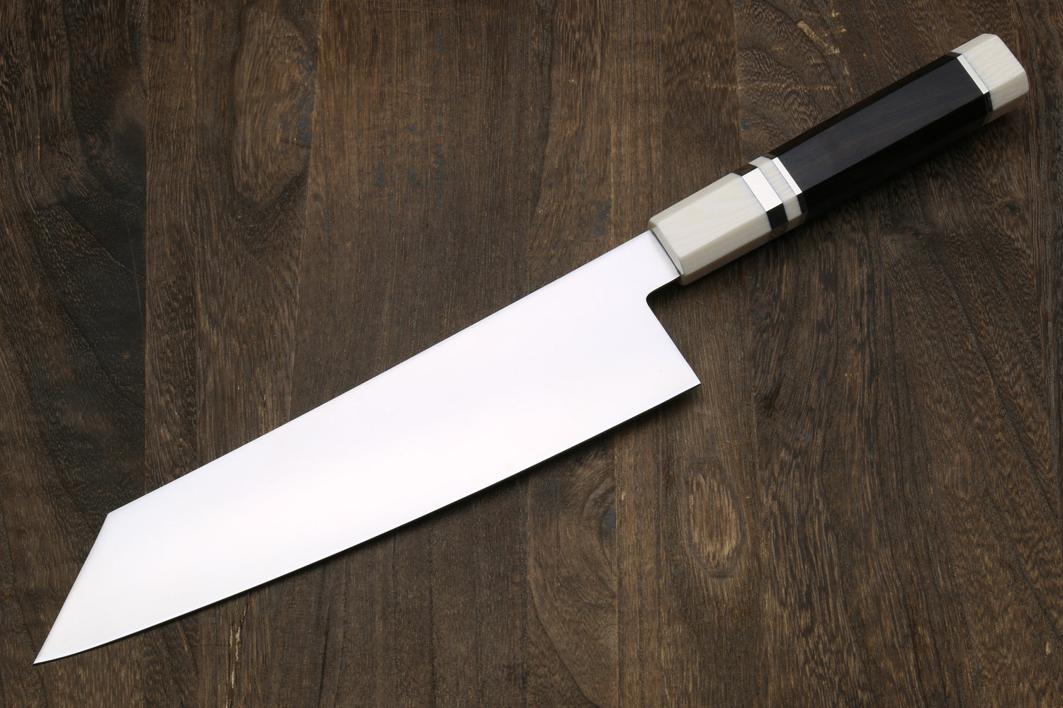 Kiritsuke chef knife with stainless blade and ebony handle with ivory bolster accents.