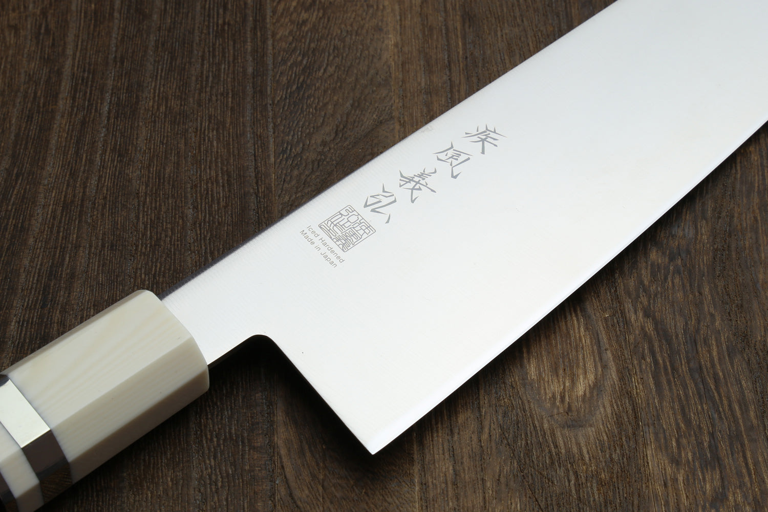 Kiritsuke chef knife blade with Japanese-style engraving on stainless steel.