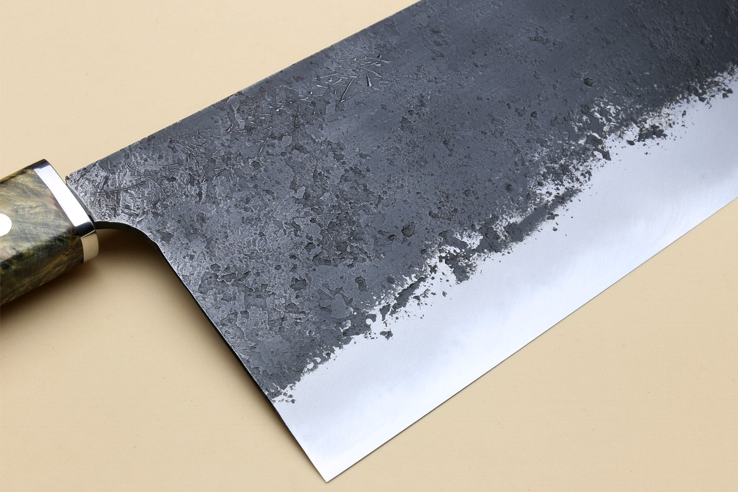 Chinese-style cleaver blade close-up with speckled dark steel face and sharp edge