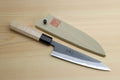 Kurouchi-finished blue steel petty knife with light wood handle and light wood sheath cover.