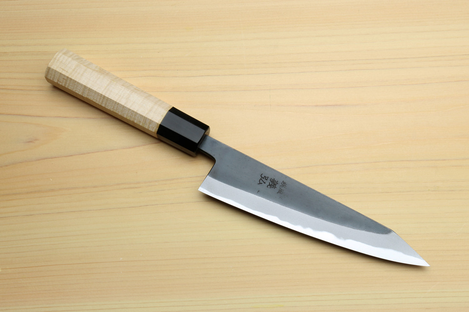 Kurouchi-finished blue steel petty knife with light wood handle, black bolster, and sharp tip.