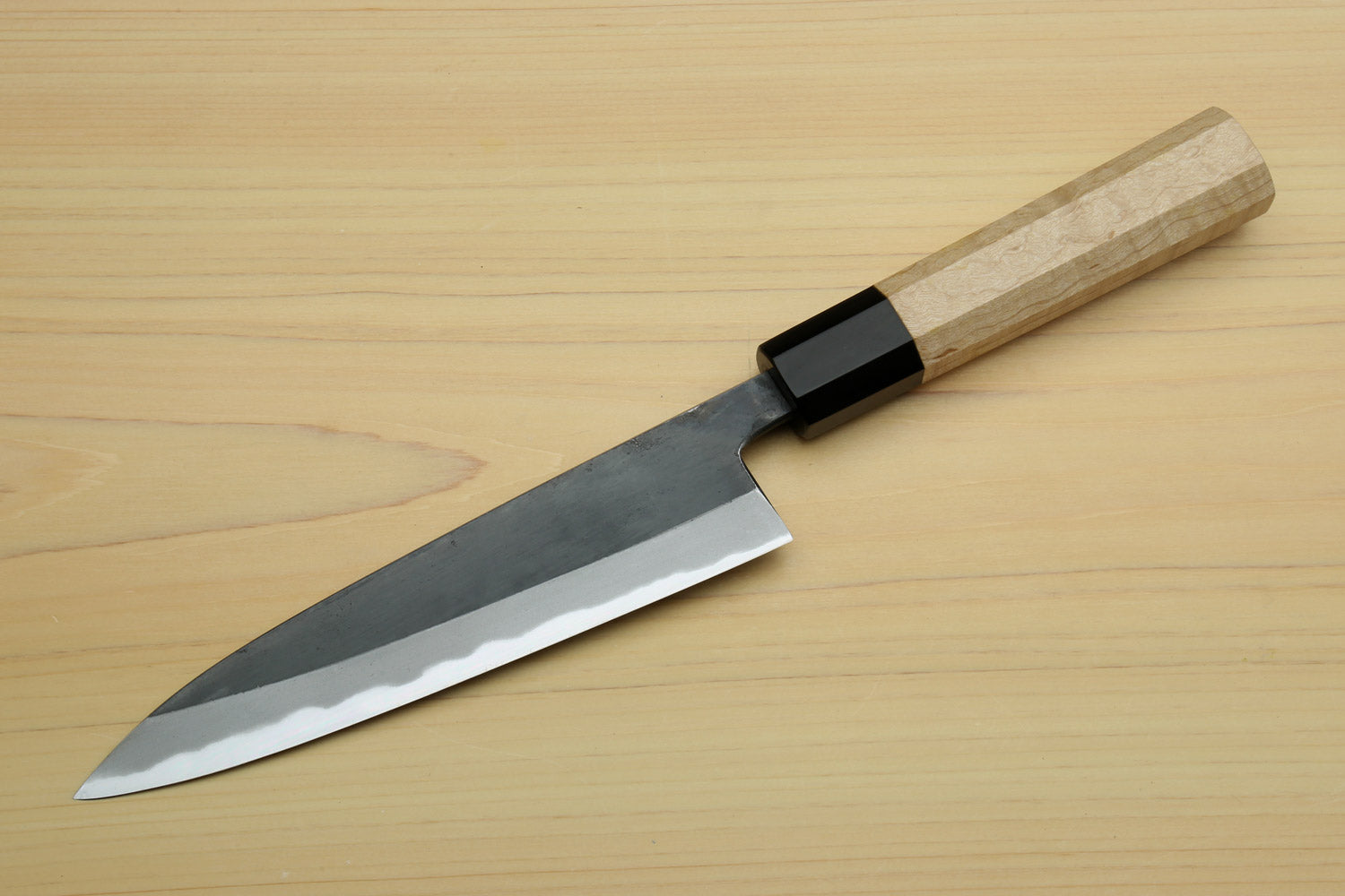 Petty utility knife with dark blade, white-steel edge, and light wood handle with black bolster