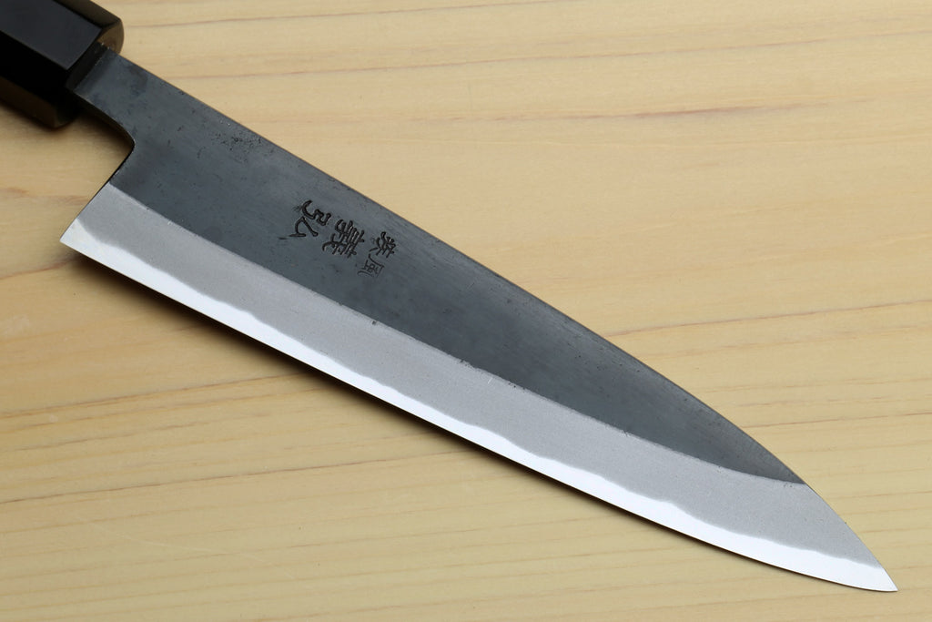Petty utility knife blade close-up with engraved markings and white cutting edge