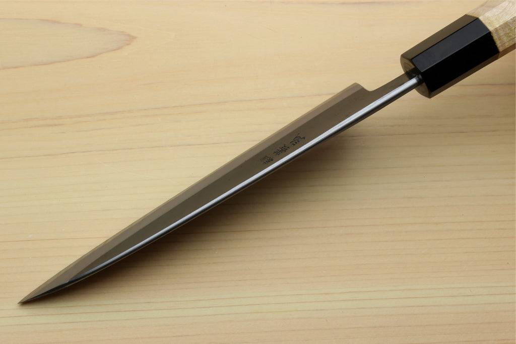 Petty utility knife with silver blade and light wood handle, black bolster near tip