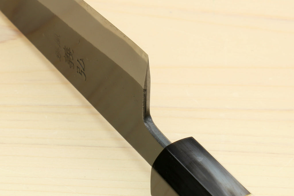 Kurouchi-finished blue steel knife tip and side profile with dark handle bolster.