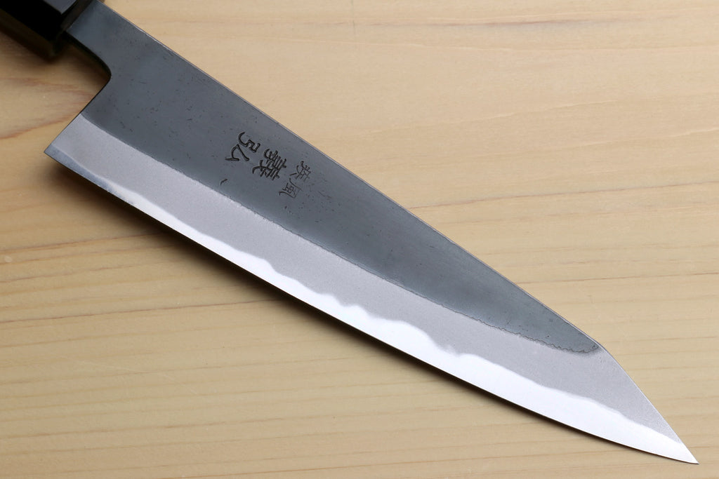 Kurouchi-finished blue steel knife blade angled view with engraved characters.