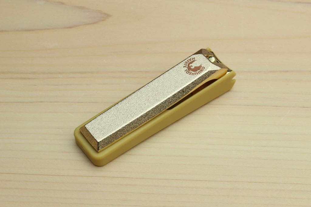 Gold nail clipper with silver blade and engraved top logo detail.