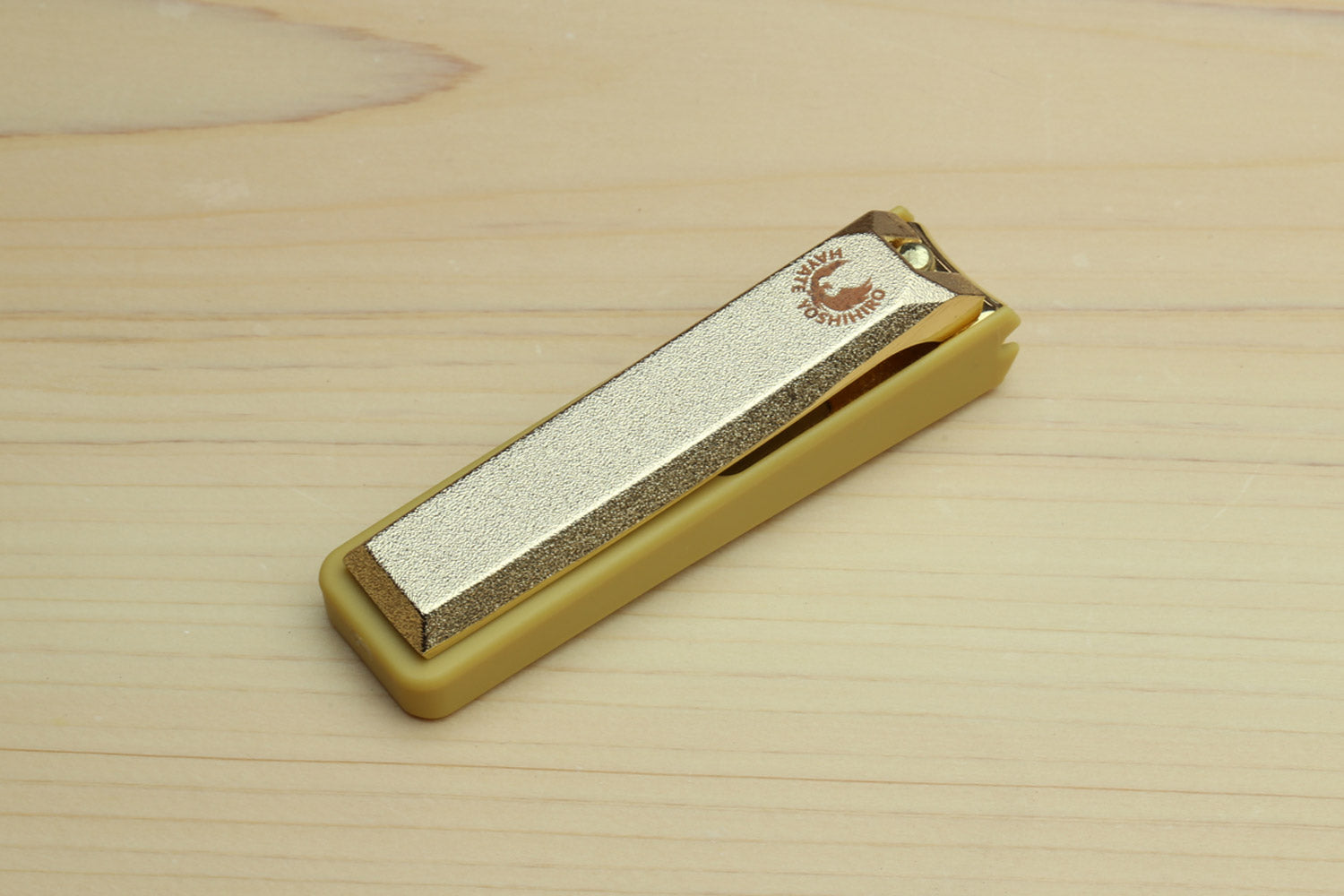 Gold nail clipper with silver blade and engraved top logo detail.