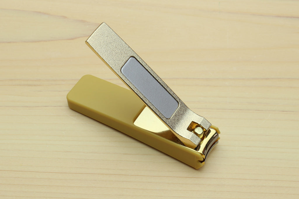Gold-colored nail clipper with silver textured blade and lever.