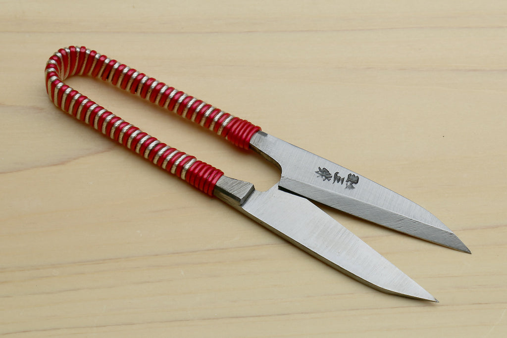Japanese sewing snip scissors laid flat, red string-wrapped handle and pointed blades
