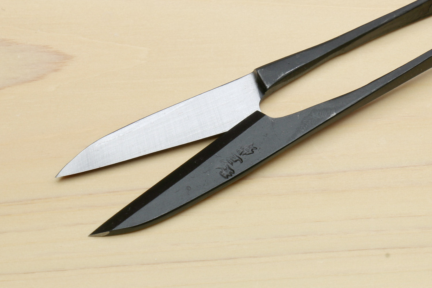 Japanese sewing snip scissors with silver blades and black handle, angled