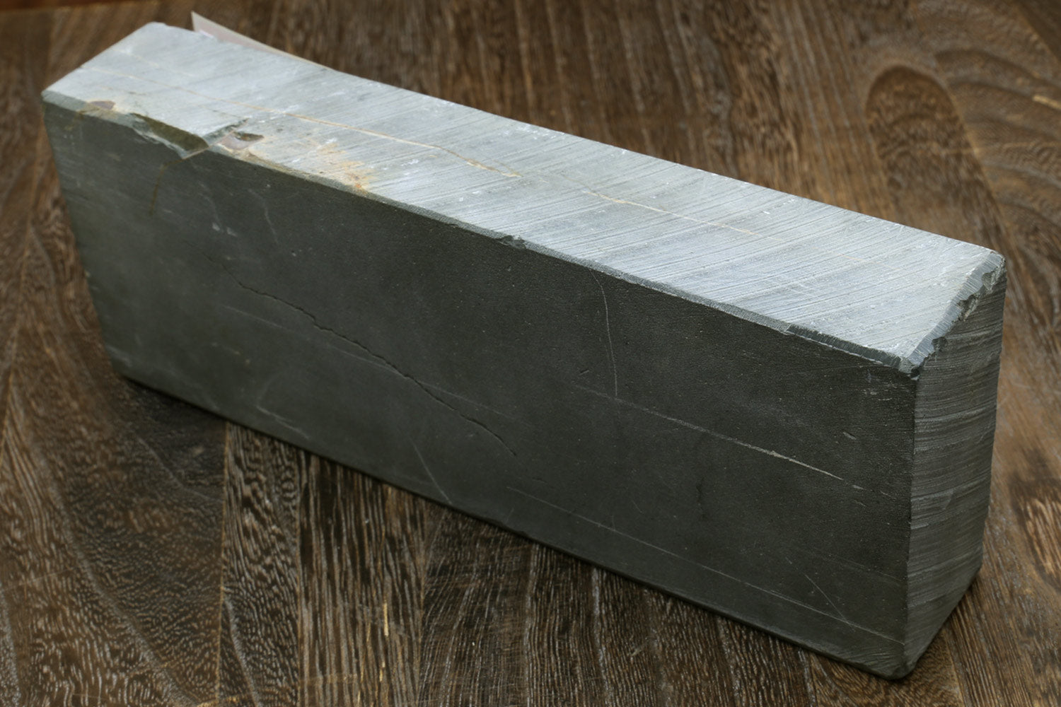 Natural sharpening whetstone block, dark gray sides with pale top surface