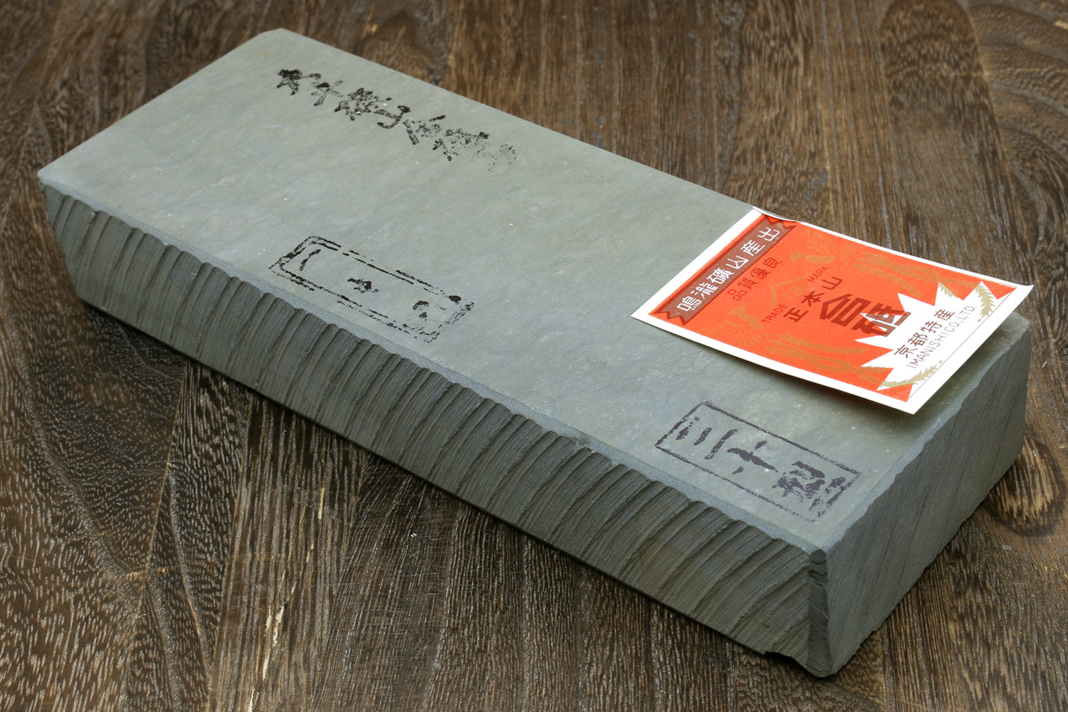 Natural sharpening whetstone with label, rectangular gray stone, flat top and beveled edge
