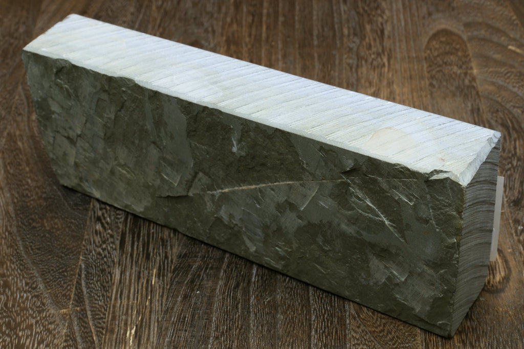 Natural sharpening whetstone, rectangular dark gray stone with flat top and rough side texture