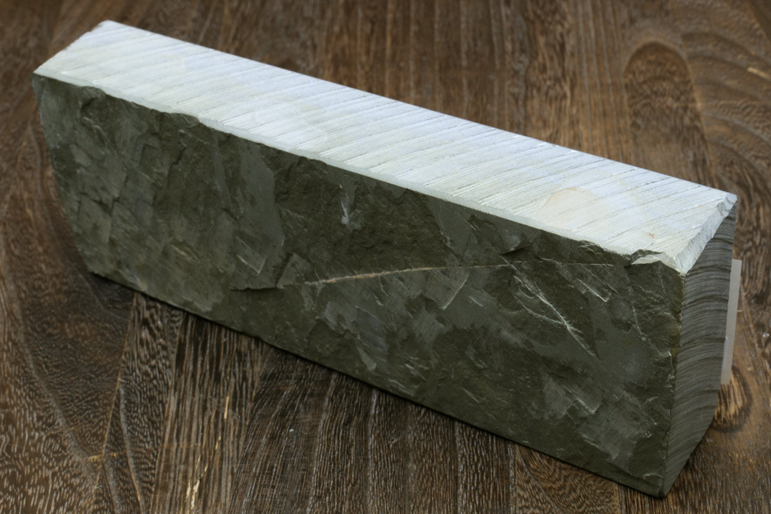 Natural sharpening whetstone, rectangular dark gray stone with flat top and rough side texture