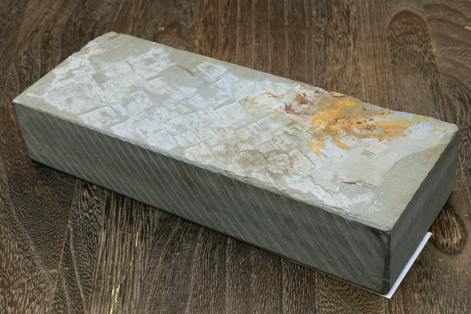 Natural sharpening whetstone, long rectangular stone with light top surface and orange discoloration