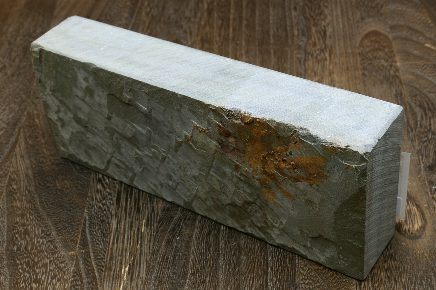 Natural sharpening whetstone, dark gray rectangular stone with rough face and mineral stains