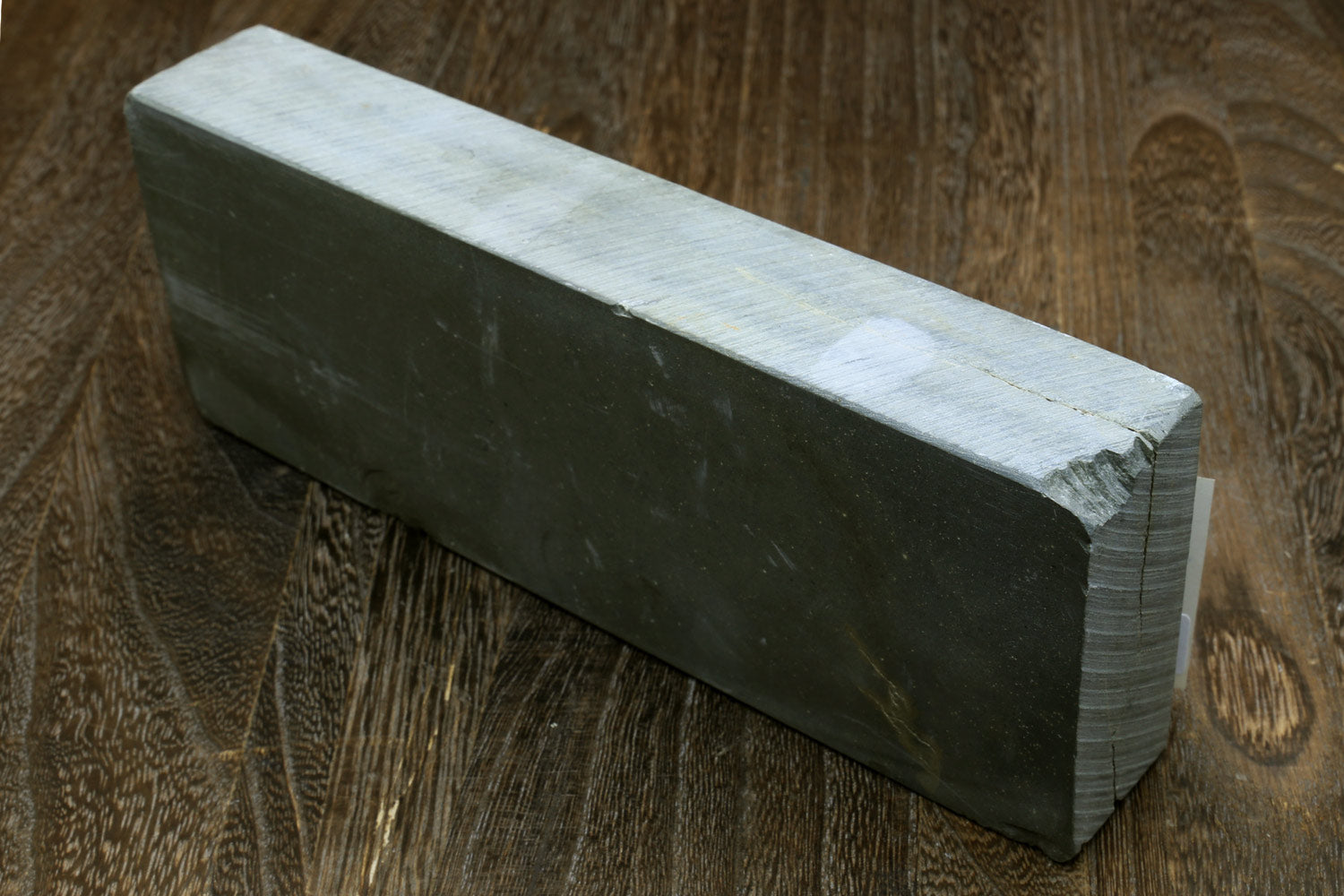 Natural sharpening whetstone block, dark side view with stacked edge layers