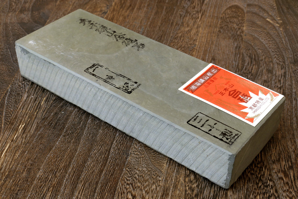 Natural sharpening whetstone, light gray with pale green mottled surface and paper label