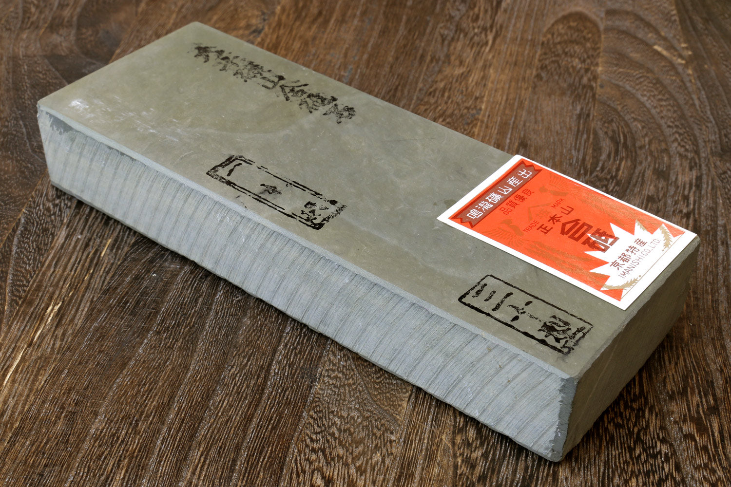 Natural sharpening whetstone, light gray with pale green mottled surface and paper label