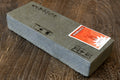 Rectangular sharpening whetstone with paper label on one face, gray stone body