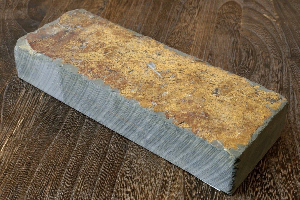 Natural whetstone block with yellow-brown speckled surface and gray edges