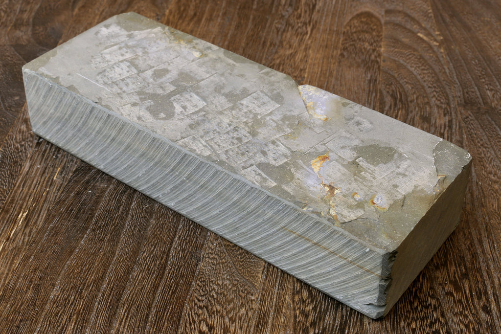 Natural whetstone sharpening block with worn surface markings