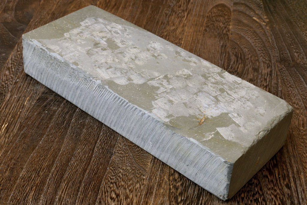 Natural whetstone finishing stone, rectangular pale gray stone block with speckled marks