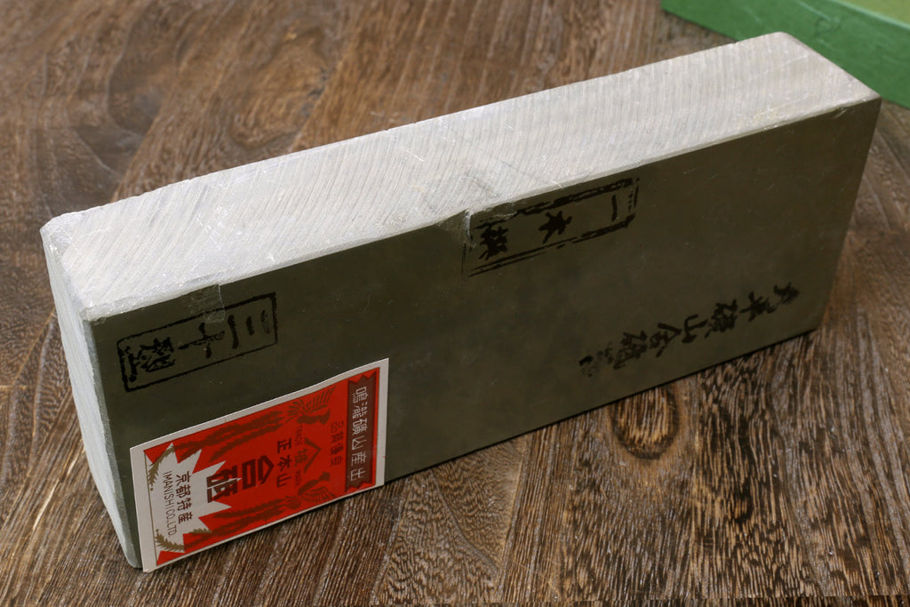 Natural sharpening whetstone, rectangular stone block with label stickers on the side