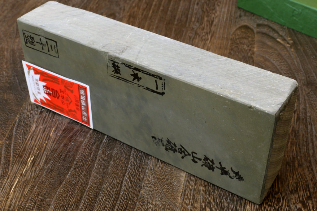 Natural sharpening whetstone, long light-gray stone block with printed text on side