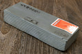 Gray sharpening whetstone block with side orange label and etched markings