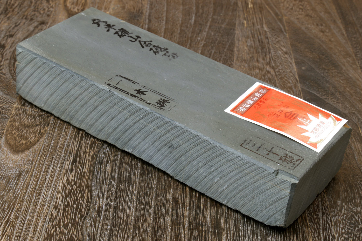 Gray sharpening whetstone block with side orange label and etched markings
