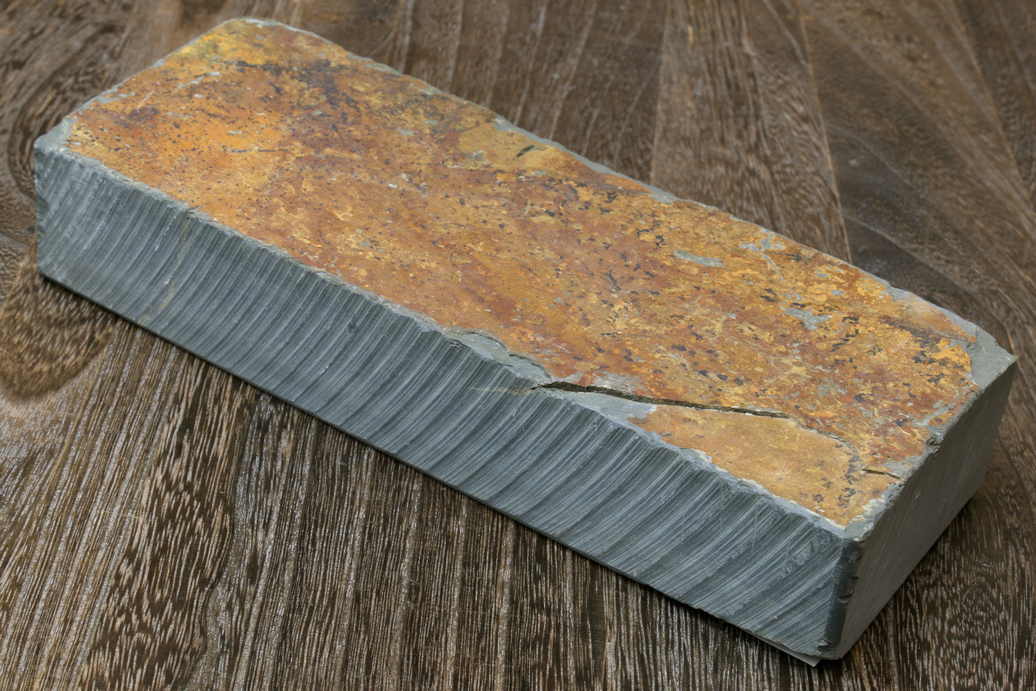 Mottled brown and gray sharpening whetstone block with engraved text on end