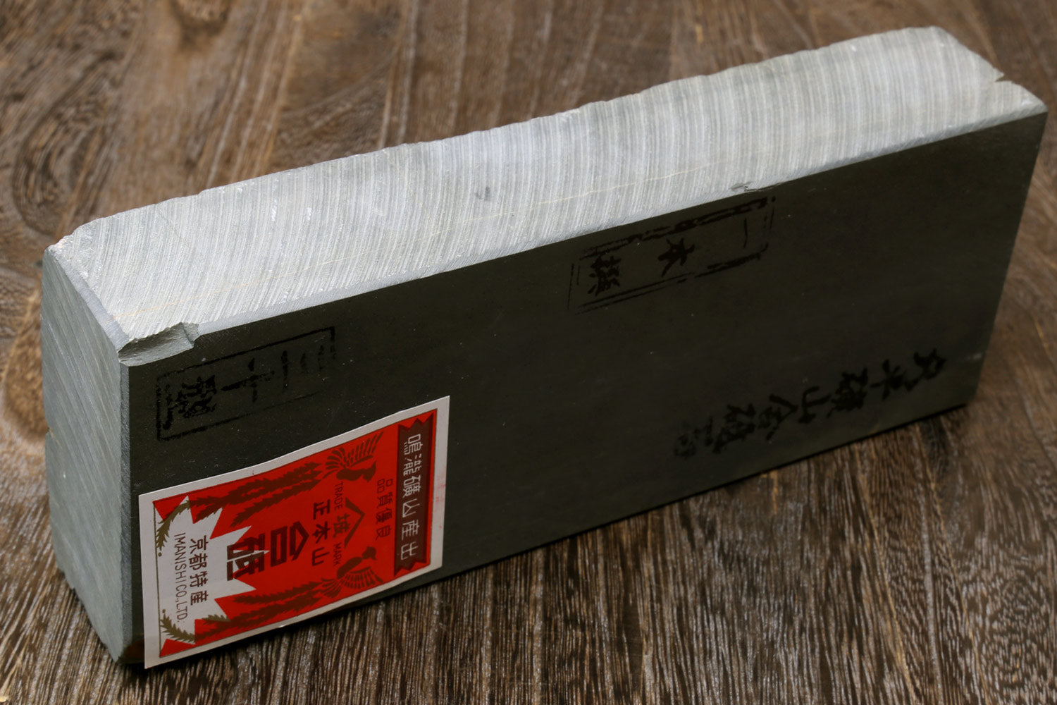 Light gray sharpening whetstone block with red-orange label and engraved markings