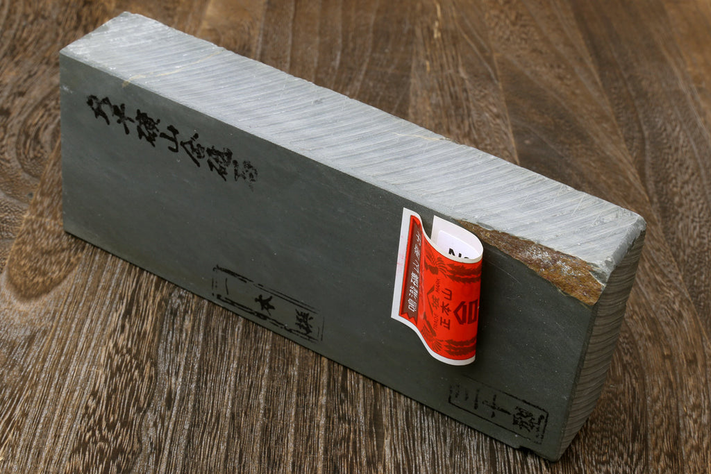 Light gray sharpening whetstone block with red-orange label on dark end